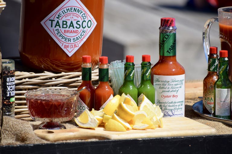 A vibrant display of Tabasco sauce bottles, lemon slices, and spices on a wooden board.