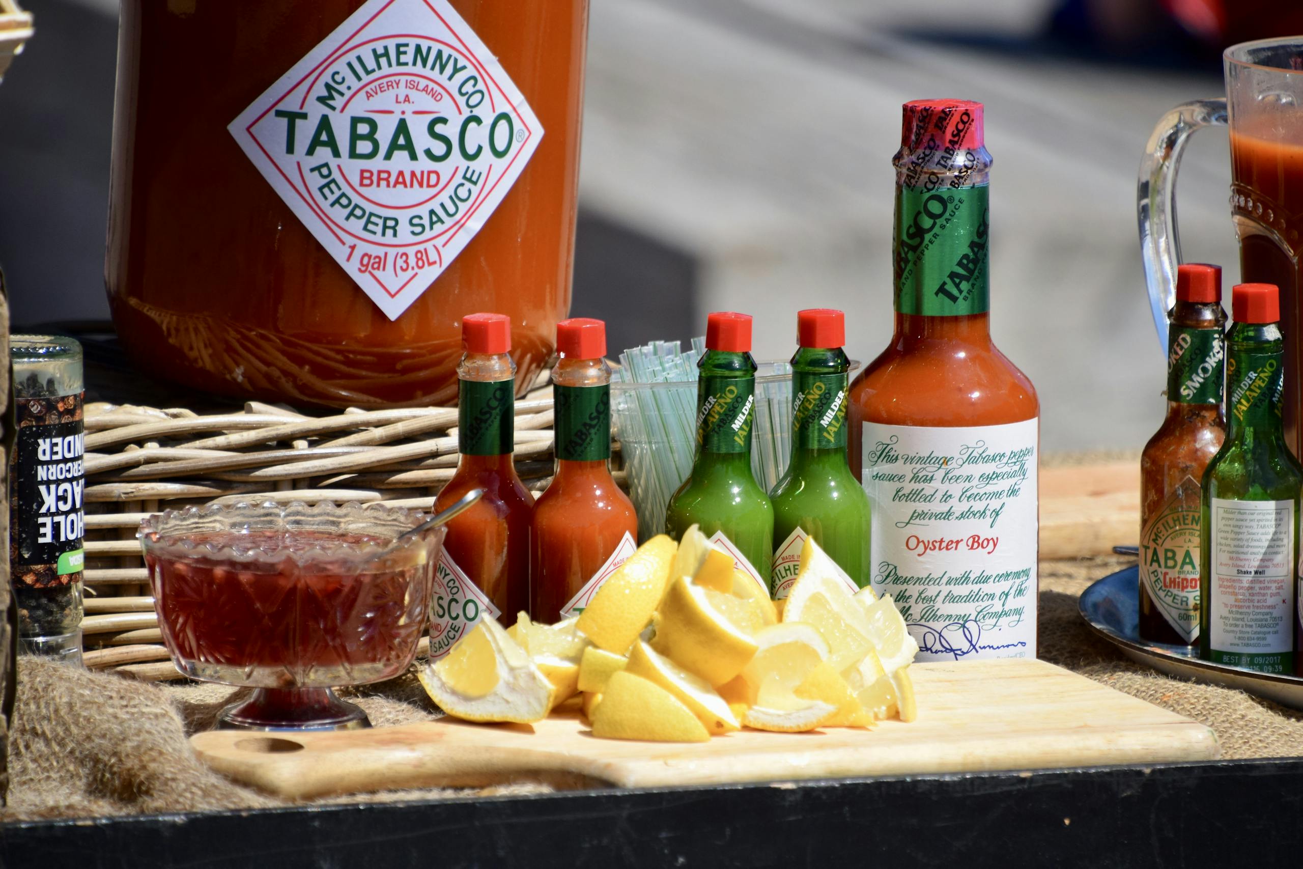 A vibrant display of Tabasco sauce bottles, lemon slices, and spices on a wooden board.