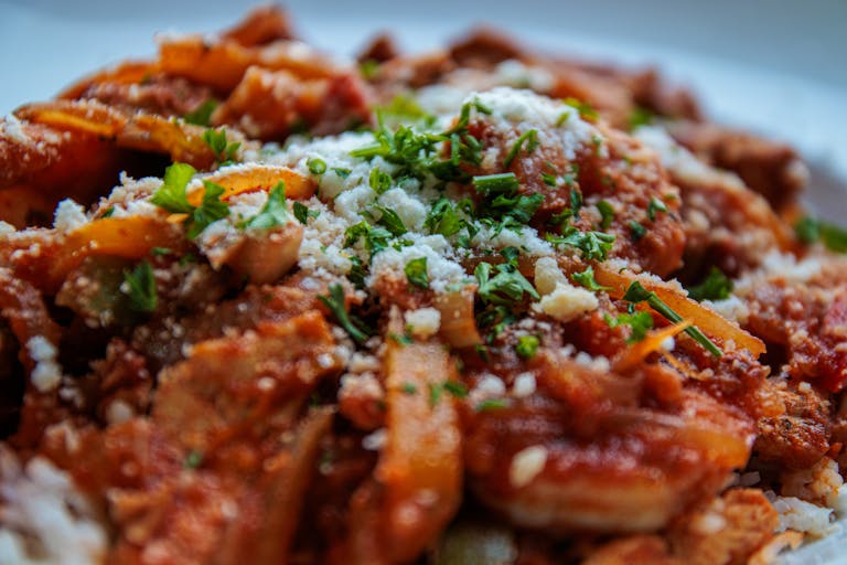Close-up of a savory pasta dish topped with fresh herbs and cheese.
