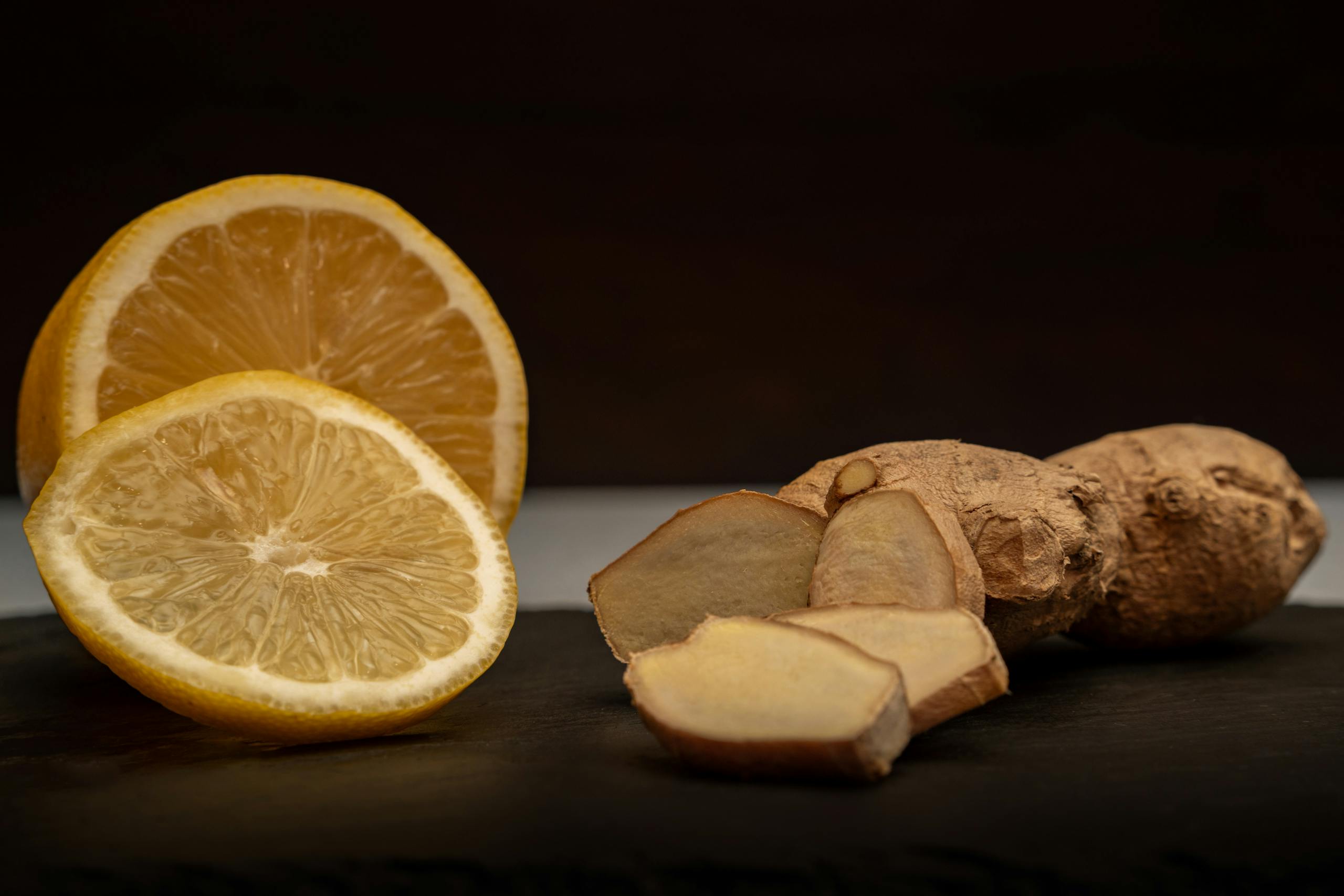 Close-up of fresh ginger root and lemon slices, highlighting their vibrant natural textures and health benefits.
