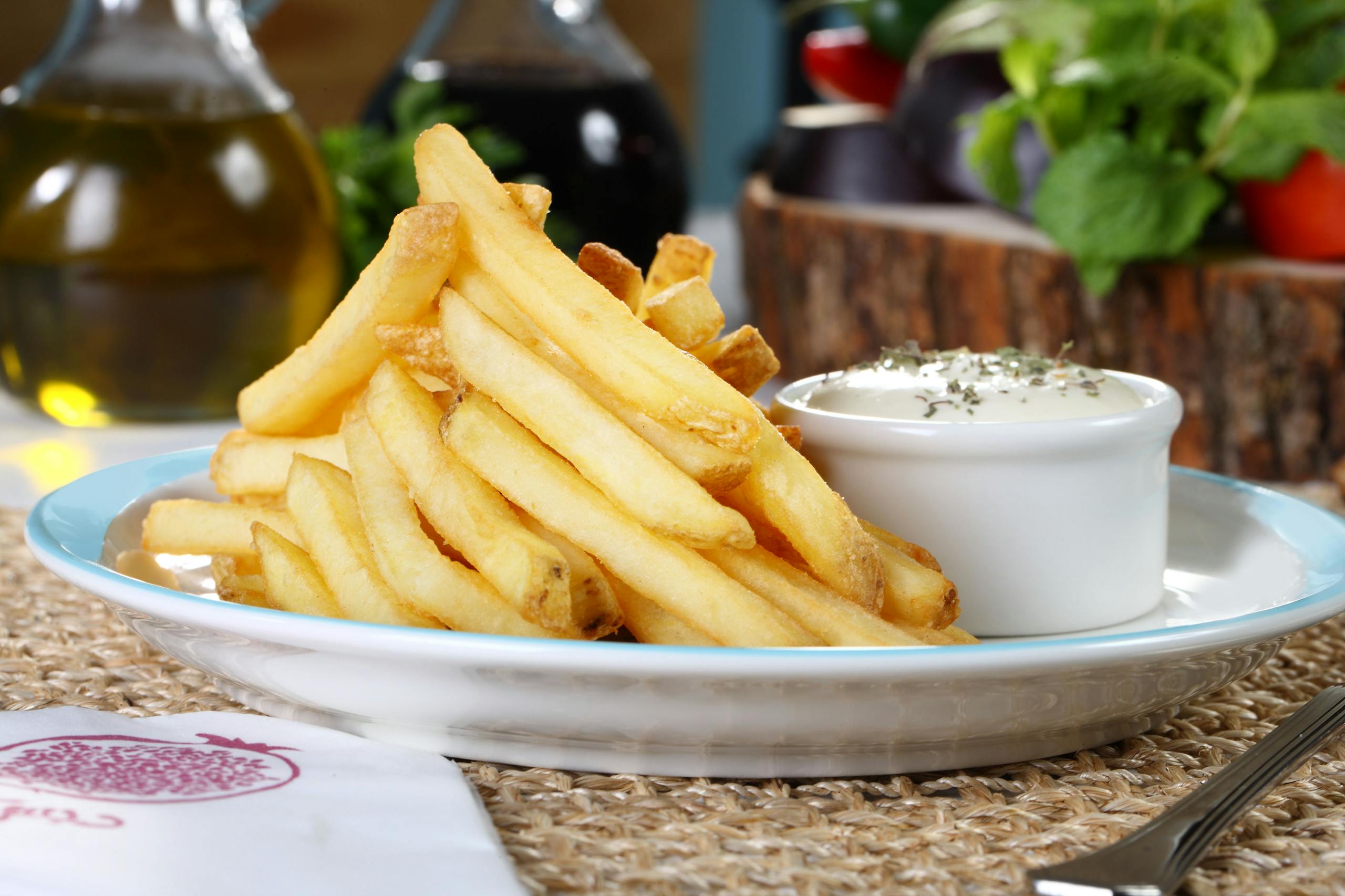 Crispy golden French fries served with a creamy dip in a cozy setting.