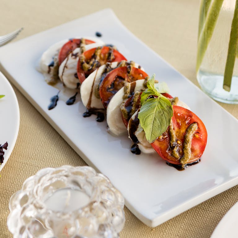 Delicious Caprese salad with fresh mozzarella, tomatoes, and basil drizzled with balsamic glaze.