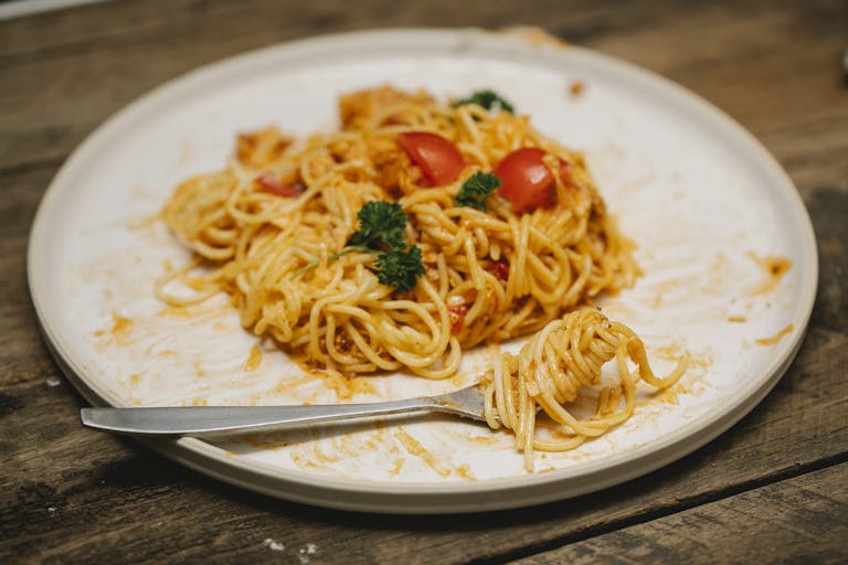 Freshly cooked spaghetti with tomatoes and parsley on a rustic table setting, inviting and appetizing.