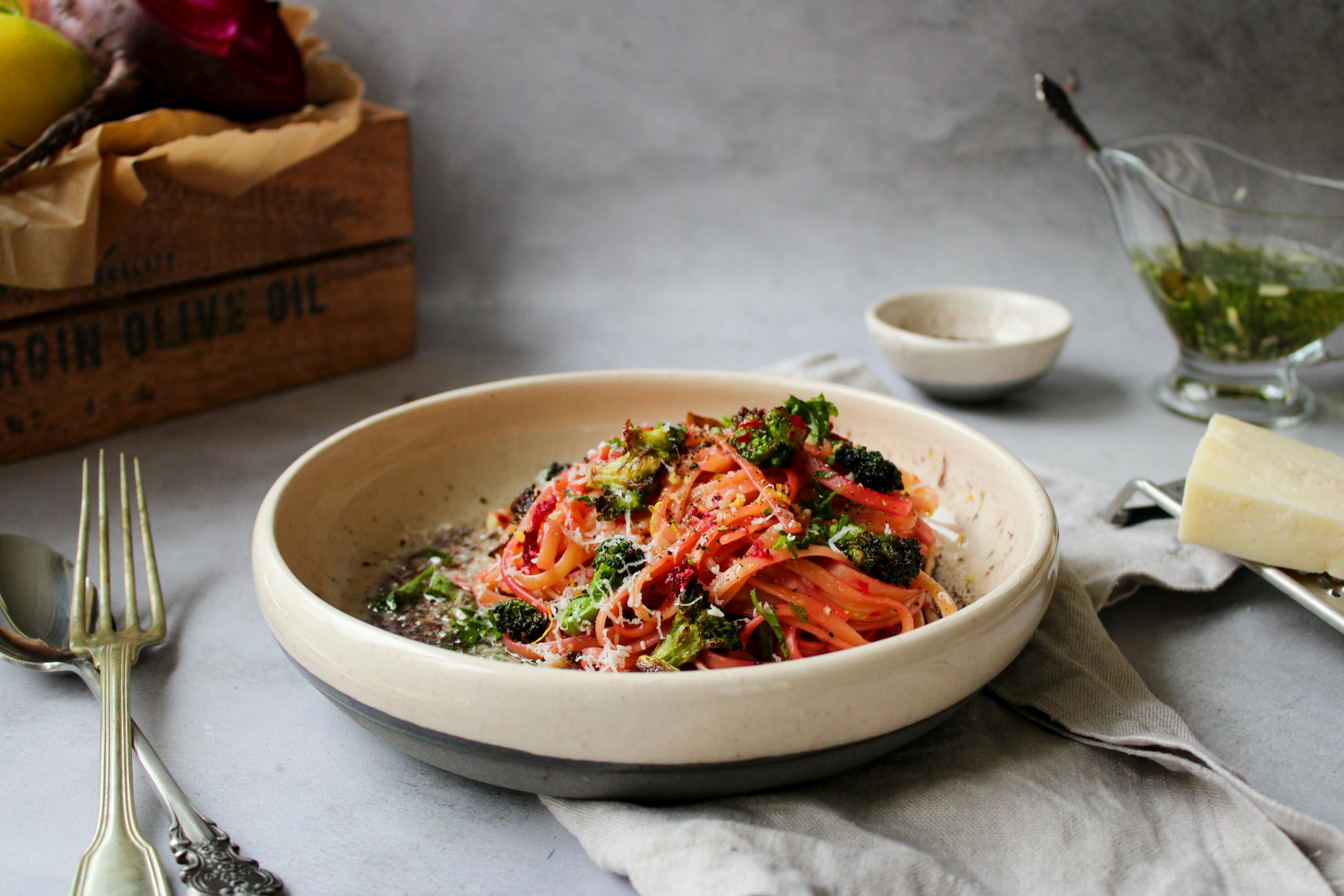 Gourmet pasta served in a shallow bowl with fresh herbs and broccoli.