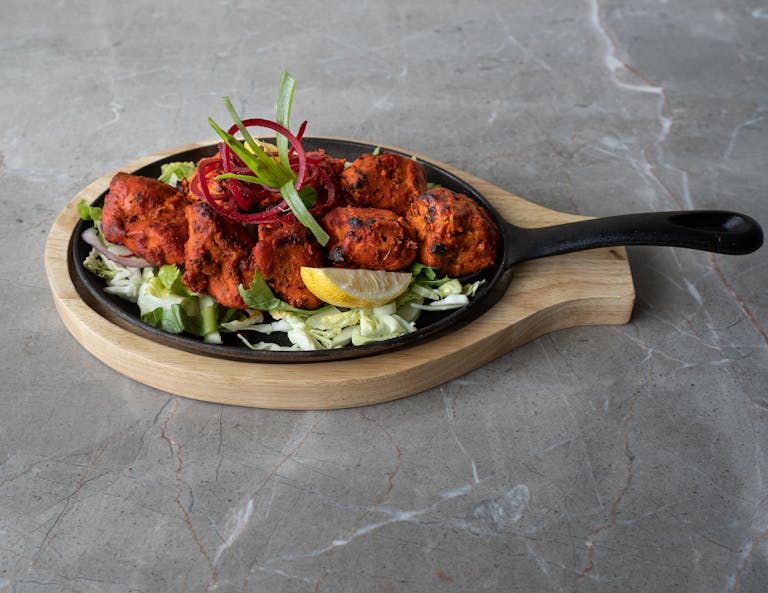 Mouthwatering tandoori chicken arranged on a sizzling platter, perfect for authentic Asian cuisine lovers.