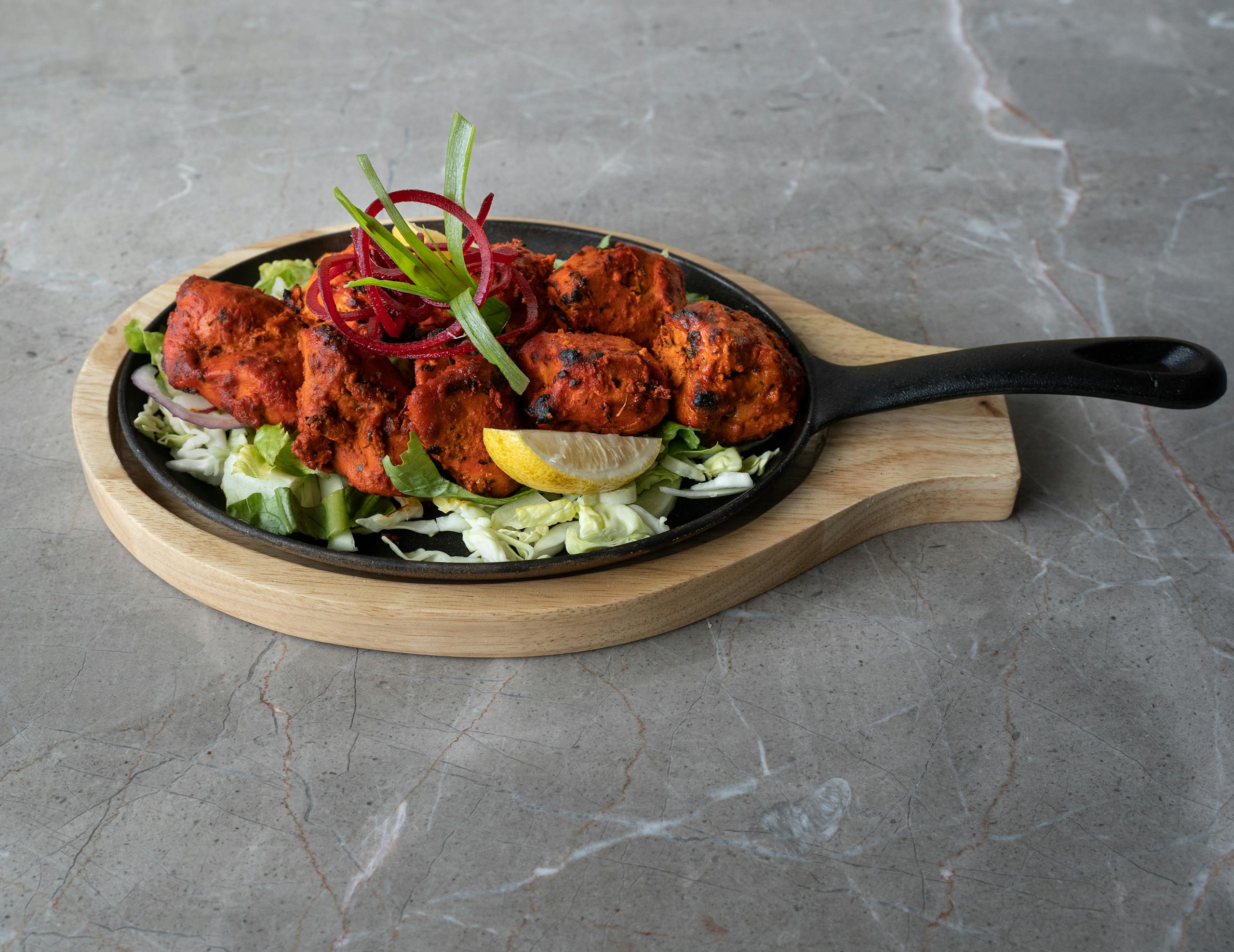 Mouthwatering tandoori chicken arranged on a sizzling platter, perfect for authentic Asian cuisine lovers.