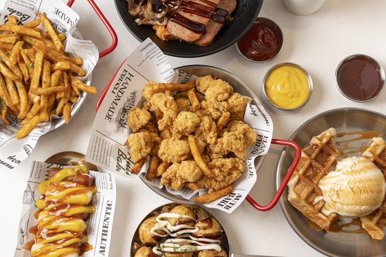 Top view of assorted fast food dishes, including fried chicken, waffles, and fries.